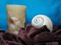 White sea shell and candle on folded scarf Royalty Free Stock Photo