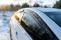 A white sedan car close up on a winter countryside road, landscape, covered in snow ice against sunset, sun reflection Royalty Free Stock Photo