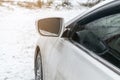 A white sedan car on winter countryside road covered in snow ice close-up, reflection in the window. Snow layer on Royalty Free Stock Photo