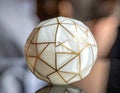White segmented sphere with gold lines on reflective surface Royalty Free Stock Photo