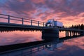 white semi-truck driving on a bridge over calm water at dusk Royalty Free Stock Photo