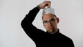 White serious attractive man in glasses puts a tinfoil helmet to the brains on his head. Emotional handsome guy with glasses. Royalty Free Stock Photo