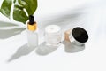 White serum bottle and cream jar, mockup of beauty product brand. Top view on the white background.