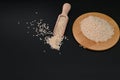 Sesame seeds in a wooden plate on a black background, next to a wooden spoon with sesame seeds. Selective focus. Royalty Free Stock Photo