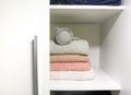 White shelf of the home wardrobe with colorful sweaters, jumpers and warm headphones. Small space organization