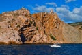 white ship sails in Black sea near big red rock, mountain, summer sunset, vacation Royalty Free Stock Photo