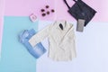 white shirt, blue jeans, brown purse and black bag on multi pastel color background