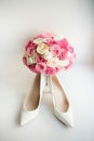 White shoes for a bride stand before pink wedding bouquet Royalty Free Stock Photo