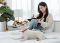 White short hair parson jack russell terrier dog laying lying down on bed with Asian young cheerful female owner sitting smiling Royalty Free Stock Photo