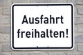 A white sign on a brick wall, with the words `Ausfahrt freihalten`, translation: keep gateway clear Royalty Free Stock Photo