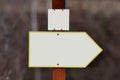 White signpost with yellow edge and empty space, empty natural orientation tourist arrow in the forest, empty copy space, blurred