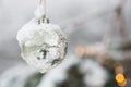 White Silver Beautyful Christmas Ornament Bauble haning at a Fir Tree with Snow