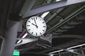 White simple clock hanging on pole in station