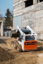 White skid steer loader at a construction site working with a soil. Industrial machinery. Industry. Royalty Free Stock Photo