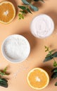 White skin cream, salt, green leaves and oranges on a beige background, top view.