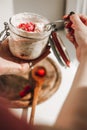 A white skin woman holding spoon of muesli in her hands with a spoonful of granola with strawberries, with nutritious Royalty Free Stock Photo