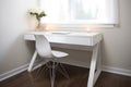 a white, sleek desk with a modern chair and laptop on it