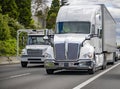 White small and big rigs semi trucks with semi trailers running side by side on the wide multiline highway road Royalty Free Stock Photo