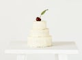 White small cake on three floors decorated fresh cherry on top. Royalty Free Stock Photo