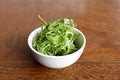 White porcelain bowl with rocket herb on brown table