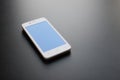 White Smart Phone With Blue Screen on the Black Table Royalty Free Stock Photo