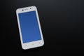 White Smart Phone With Blue Screen on the Black Table Royalty Free Stock Photo