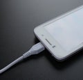 White Smart Phone Charging with USB Cable on Black Table Royalty Free Stock Photo