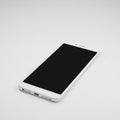 White smartphone with a black screen, positioned angled on a plain light surface. The Royalty Free Stock Photo