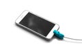 The white smartphone is connected to the wired charging. On the wire toy in the form of a blue crocodile. Close up. Isolated on wh Royalty Free Stock Photo