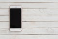 White smartphone iphone with dark screen on white wood texture background Royalty Free Stock Photo