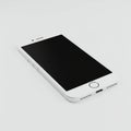 A white smartphone with a sleek design is angled on a plain white surface. The device Royalty Free Stock Photo