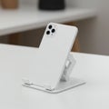 A white smartphone with a triple-camera setup is placed on a minimalist, adjustable Royalty Free Stock Photo