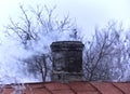 White smoke from the chimney of an old house during frost Royalty Free Stock Photo