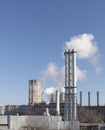 White smoke comes from a white chimney heat station pipe on a blue sky background.