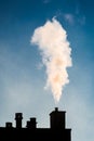 White smoke coming out of a chimney on the roof of a residential building Royalty Free Stock Photo