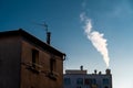 White smoke coming out of a chimney on the roof of a residential building Royalty Free Stock Photo