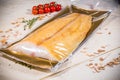 White smoked fish in a sealed vacuum packaging on the background of vegetables and fruits lemon pepper