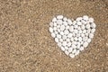 White smooth pebble romantic heart shape on sunny sand beach top view Royalty Free Stock Photo