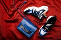 White sneakers with black and blue inserts on a thick figured sole and a blue bag with a gold chain on a red woven background Royalty Free Stock Photo