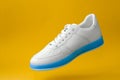 white sneakers with blue sole isolated on yellow background Royalty Free Stock Photo