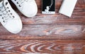 White sneakers, earphone with phone and charger on wooden background. Concept healthy lifestyle. Sports flatlay. Top view. Place