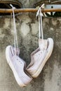 White sneakers hung around with wood and cement wall as a background.