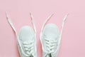 White sneakers on a pink background with untied laces. Flat lay. top view Royalty Free Stock Photo