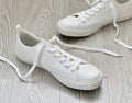 White sneakers with untied laces are on floor