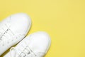 White sneakers on yellow background top view flat lay. Stylish youth women`s leather sneakers, sports shoes, genuine leather