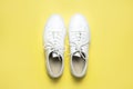 White sneakers on yellow background top view flat lay. Stylish youth women`s leather sneakers, sports shoes, genuine leather