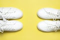 White sneakers on yellow background top view flat lay. Stylish youth women`s leather sneakers, sports shoes, genuine leather