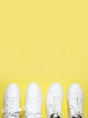 White sneakers on yellow background top view flat lay. Stylish youth women`s leather sneakers, sports shoes, genuine leather