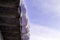 White snow and icicles hanging from the slate roof against the blue sky