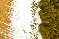 White snow melts on a green agricultural field. Aerial view